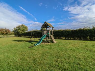 A playground structure with a slide and swings in a field at Fisherman's Rest Ipswich