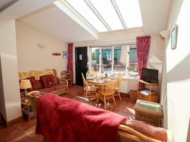 A living room with a sofa and dining area at Coachman's Cottage Ipswich