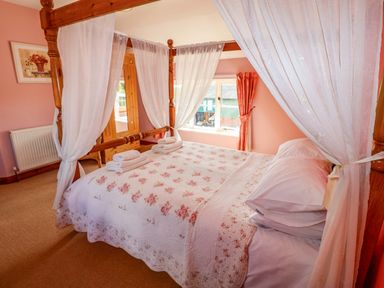A bedroom with a four-poster bed and towels at Coachman's Cottage Ipswich