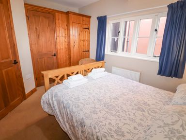 A bedroom with a bed and wardrobe at Coachman's Cottage in Ipswich