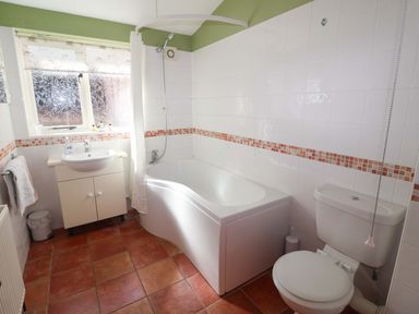 A bathroom with a bathtub and sink at Coachman's Cottage Ipswich
