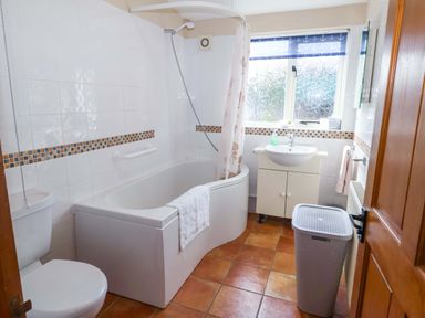 A bathroom with a bath tub, shower, and sink at Churn House in Ipswich