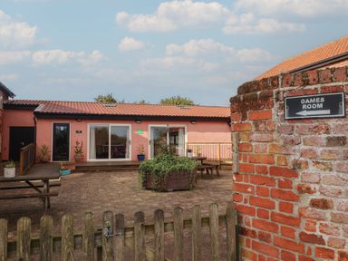 An outdoor area with games room sign and seating at Blacksmith's Cottage in Ipswich