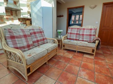 A snug with rattan sofas and a coffee table at Wheelwright's Cottage Ipswich