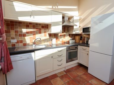 A kitchen with a sink, dishwasher, oven, and refrigerator at Wheelwright's Cottage in Ipswich