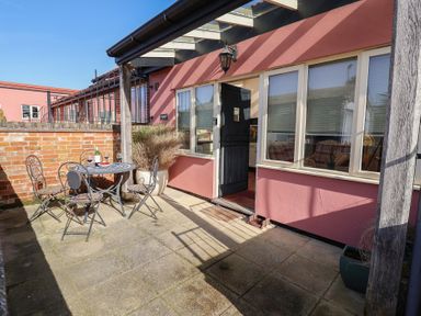 An outdoor patio with a table and chairs at Wheelwright's Cottage Ipswich