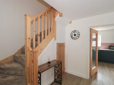 A hallway with stairs and a wall clock at 3 The Stables in Highbridge