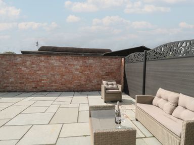 Outdoor seating area with a glass table and wine glasses at 3 The Stables Highbridge