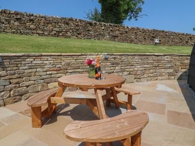 An outdoor patio with a wooden table and benches at Ogden in Nelson