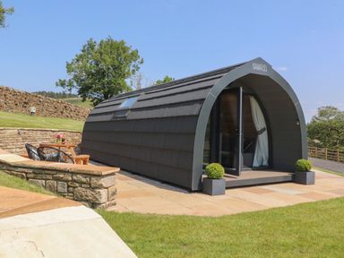 A cabin with outdoor seating and a stone wall at Ogden in Nelson