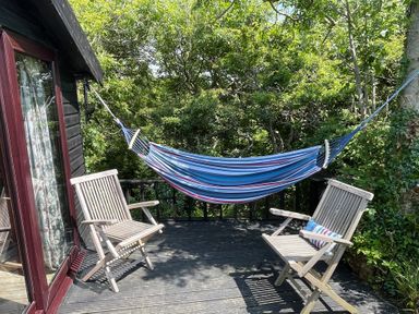An outdoor space with a hammock and two wooden chairs at The Tree House in Nine Wells near Solva