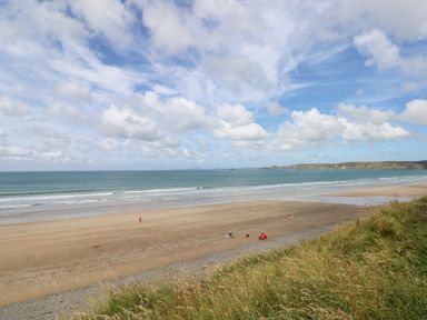 A beach with sand and sea at The Shephard Hut Nine Wells near Solva