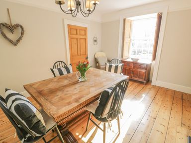 A dining room with a table and chairs at Bwthyn Morse Llanfair