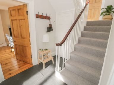 A hallway with a staircase and table at Bwthyn Morse in Llanfair