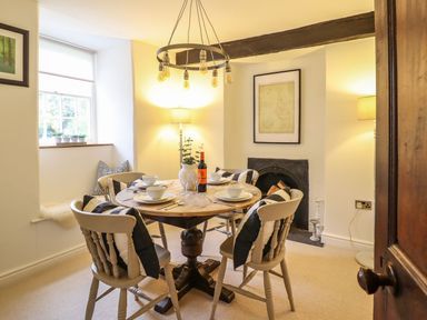 A dining room with a round table and chairs at Bwthyn Canol in Llanfair