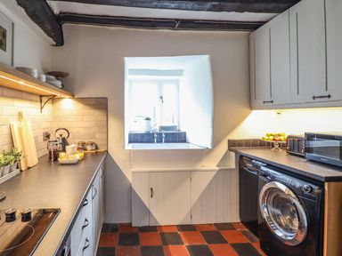 A kitchen with a window and a washing machine at Bwthyn Canol in Llanfair