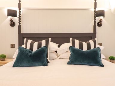 A bedroom with a bed and decorative pillows at Bwthyn Canol in Llanfair