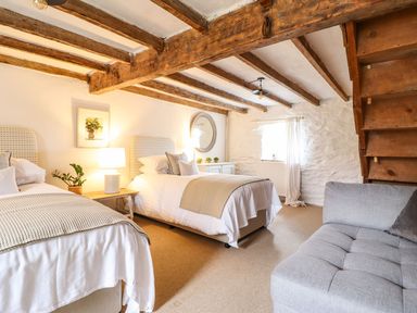 A bedroom with two beds and a staircase at Bwthyn Canol in Llanfair