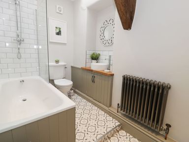 A bathroom with a bathtub, toilet, sink, and mirror at Bwthyn Canol in Llanfair