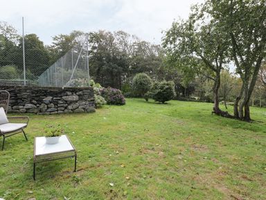 A garden area with a stone wall and seating at Bwthyn Canol in Llanfair