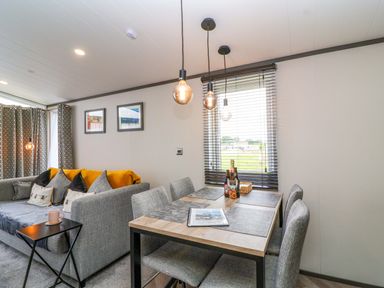 A living room with a sofa and dining area at Hazelnut Lodge in Chipping Norton