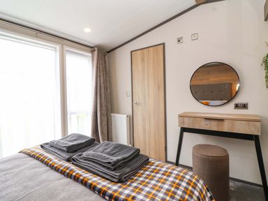 A bedroom with a bed and a dressing table at Hazelnut Lodge in Chipping Norton