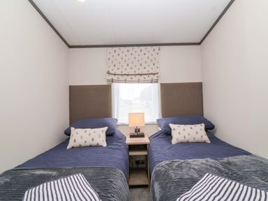 A bedroom with two single beds and a lamp at Hazelnut Lodge in Chipping Norton