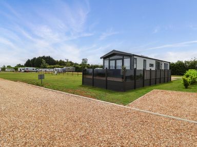 An outdoor scene with a holiday lodge and caravans at Hazelnut Lodge in Chipping Norton