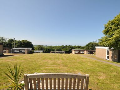 A garden with grass and a bench at 8 Hillside in Bude
