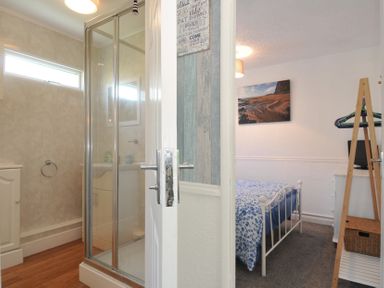 A bedroom with a bed and a shower area at 8 Hillside in Bude