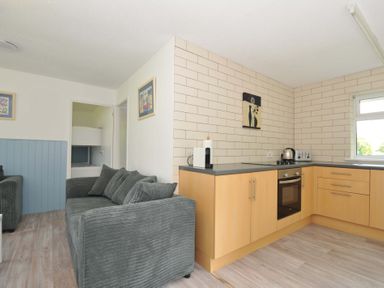 A living room with a sofa and kitchen unit at 4 Rosecraddoc Lodge Holiday Bungalows Liskeard