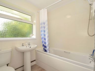 A bathroom featuring a bathtub, toilet, sink, and window at 4 Rosecraddoc Lodge Holiday Bungalows in Liskeard