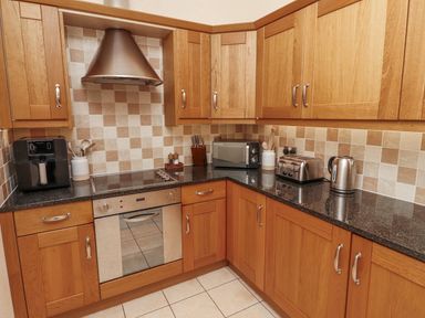 A kitchen with cabinets and appliances at Watermill Cottage North Charlton