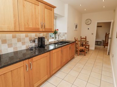 A kitchen with wooden cabinets and a table at Watermill Cottage in North Charlton