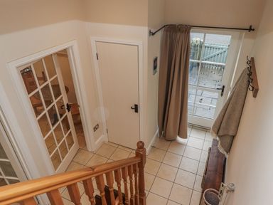 A hallway with stairs and a glass door at Watermill Cottage in North Charlton