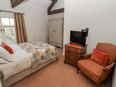 A bedroom with a bed and television at Watermill Cottage North Charlton