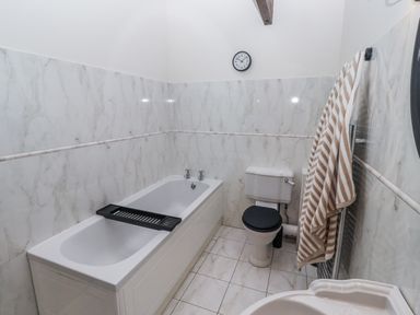 A bathroom with a bathtub and a toilet at Watermill Cottage in North Charlton