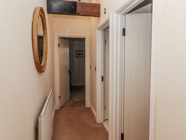 A hallway with a mirror and doors at Watermill Cottage in North Charlton