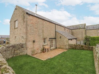 An outdoor area with a stone building and a garden at Watermill Cottage in North Charlton
