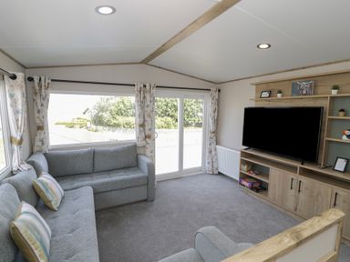 A living room with a sofa and television at Puffin Way Holiday Caravan