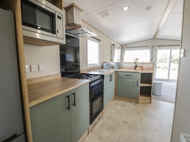 A kitchen with a microwave oven and gas stove in Puffin Way Holiday Caravan