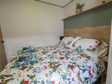 A bedroom with a bed and nightstand at Puffin Way Holiday Caravan