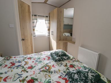 A bedroom with a bed and wardrobe at Puffin Way Holiday Caravan