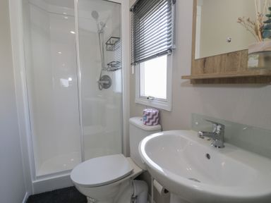 A bathroom with a shower, toilet, and sink at Puffin Way Holiday Caravan
