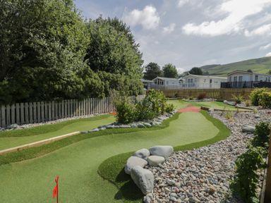 A garden with a putting green and rocks at Puffin Way Holiday Caravan 