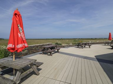 An outdoor area with picnic tables and parasols at Puffin Way Holiday Caravan