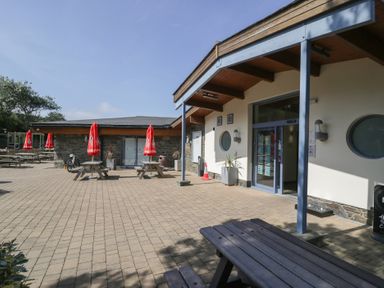 An outdoor area with benches and umbrellas at Puffin Way Holiday Caravan