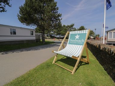 A deck chair and a sign at Sunbeach Holiday Park
