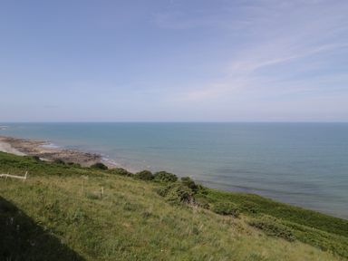 A view of the sea and shoreline with grass and rocks at Puffin Way Holiday Caravan