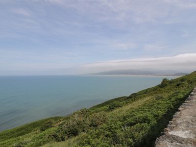A coastal view overlooking the ocean and hills at Puffin Way Holiday Caravan